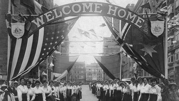 Photograph of the female staff of the Commonwealth Bank outside the Bank’s head office in Martin Place, Sydney, to cheer the returning troops and distribute cigarettes, flowers, cards and confectionary, 16 January 1919. PN-001385