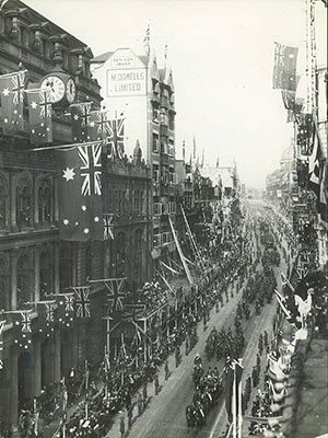 A long procession marching through a flag-decorated street.